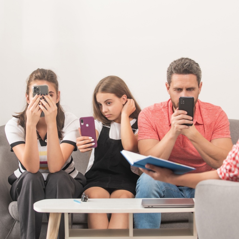 Tre persone sullo stesso divano che guardano ognuna il proprio smartphone